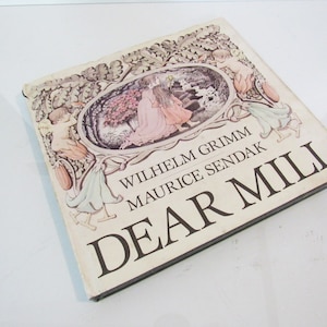 May include: A vintage hardcover book titled "DEAR MILI" by Wilhelm Grimm and Maurice Sendak. The cover features an illustration of two figures in a garden scene, framed by ornate floral and cherubic designs. The book has a worn appearance.