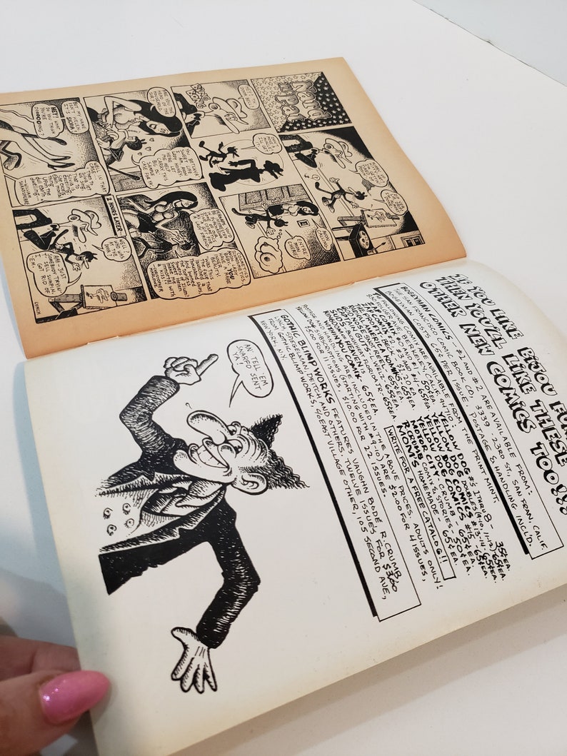 May include: Open vintage comic book pages with black and white illustrations. One page features a comic strip with speech bubbles, while the other displays a cartoon character and text. The pages are aged with a yellowed tone.