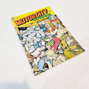 May include: A vintage comic book titled "MOTOR CITY comics" with a yellow background. The cover art depicts a chaotic scene with police officers and a crowd of people. The comic book is marked with "NO. 2" and a price of "50¢".