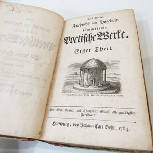 May include: An open antique book with aged, yellowed pages. The title page features ornate German script and an illustration of a domed building. The text reads "Des Herrn Friedrichs von Hagedorn sämmtliche poetische Werke. Erster Theil." Published in Hamburg, 1764.