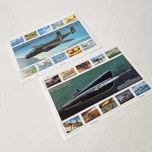 Op de afbeelding: Twee vintage ansichtkaarten. Eén toont een bommenwerper met de tekst "Aircraft of the Fighting Powers Pacific Theater of War 50th Anniversary". De andere toont een onderzeeër. Beide kaarten hebben meerdere kleinere illustraties.