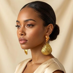 May include: Gold-colored statement earrings. The earrings have a textured, teardrop-shaped design. The earrings are a bold accessory, adding a touch of glamour. The earrings are a perfect addition to any jewelry collection.