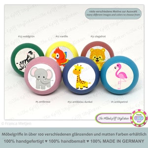 May include: Six wooden knobs with different animal illustrations and coloured backgrounds. The knobs are labelled with numbers and colour names, such as #23 waldgrün, #12 vanille, #31 ziegelrot, #5 antikroa, #32 antikblau dunkel, and #1 antikpetrol. The text "Die Möbelgriff Stylisten" is also visible.