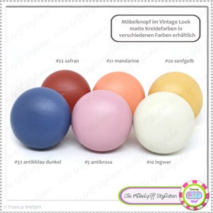Peut inclure: Six boutons ronds en bois de différentes couleurs, notamment bleu antique, rose, crème, jaune, orange et rouge. Les boutons sont étiquetés avec des numéros et des noms de couleurs, tels que #32 antikblau dunkel, #5 antikrosa et #20 senfgelb. Le texte "Möbelknopf im Vintage Look matte Kreidefarben in verschiedenen Farben erhältlich" est en haut de l'image.