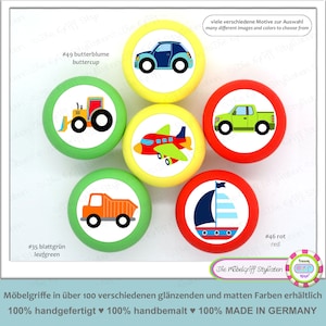 May include: Six colorful round knobs with different vehicle designs. The knobs are yellow, green, red, and blue. The vehicles include a tractor, a car, a truck, a plane, a pickup truck, and a sailboat. The knobs are labeled with the numbers 35, 46, and 49. The text "Die Möbelgriff Stylisten" is visible in the bottom right corner of the image.