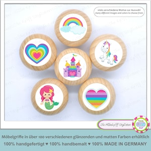 May include: Six wooden knobs with colorful illustrations. The knobs feature a rainbow, a heart, a castle, a unicorn, a mermaid, and a striped heart. The knobs are made in Germany.