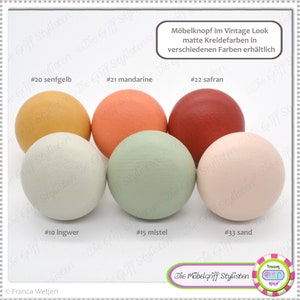 Può includere: Sei pomelli in legno di diversi colori, tra cui giallo senape, arancione, rosso, grigio chiaro, verde e rosa. I pomelli sono etichettati con numeri e nomi di colori, come #20 senfgelb, #21 mandarine, #22 safran, #10 ingwer, #15 mistel e #33 sand. Il testo "Möbelknopf im Vintage Look matte Kreidefarben in verschiedenen Farben erhältlich" è anche visibile nell'immagine.