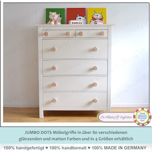 Könnte beinhalten: Weiße Kommode mit sechs Schubladen und Holzgriffen. Die Kommode hat eine helle Holzoptik und ist mit drei gerahmten Bildern von Katzen verziert. Der Text "DOMINO" ist auf einem der Bilder sichtbar.