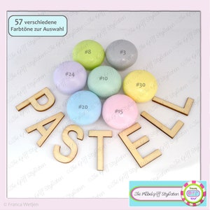 Könnte beinhalten: Pastellfarbene Holz-Knöpfe mit dem Wort "PASTEL" in Holzbuchstaben. Die Knöpfe sind in einem Kreis angeordnet, wobei das Wort "PASTEL" sie umgibt. Der Text "57 verschiedene Farbtöne zur Auswahl" ist in der oberen linken Ecke des Bildes sichtbar.