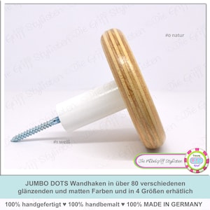 Peut inclure: Un crochet mural en bois avec une base blanche et une finition en bois naturel. Le crochet est étiqueté "#0 natur" et "#1 weiß". Le texte "JUMBO DOTS Wandhaken in über 80 verschiedenen glänzenden und matten Farben und in 4 Größen erhätlich 100% handgefertigt ♥ 100% handbemalt ♥ 100% MADE IN GERMANY" est visible en bas de l'image.