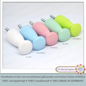 May include: A collection of six colorful wooden wall hooks in white, light blue, pink, mint green, and lime green. Each hook has a rounded knob and a threaded metal screw. The text on the image says "Die Möbelgriff Stylisten".