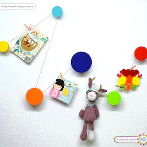 Peut inclure: Une décoration murale avec des cercles en bois colorés reliés par des cordes. L'ensemble comprend des cartes et un lapin crocheté. Les cartes présentent une illustration de paresseux et un message d'anniversaire. Les cercles sont jaunes, orange, bleus, verts et rouges.