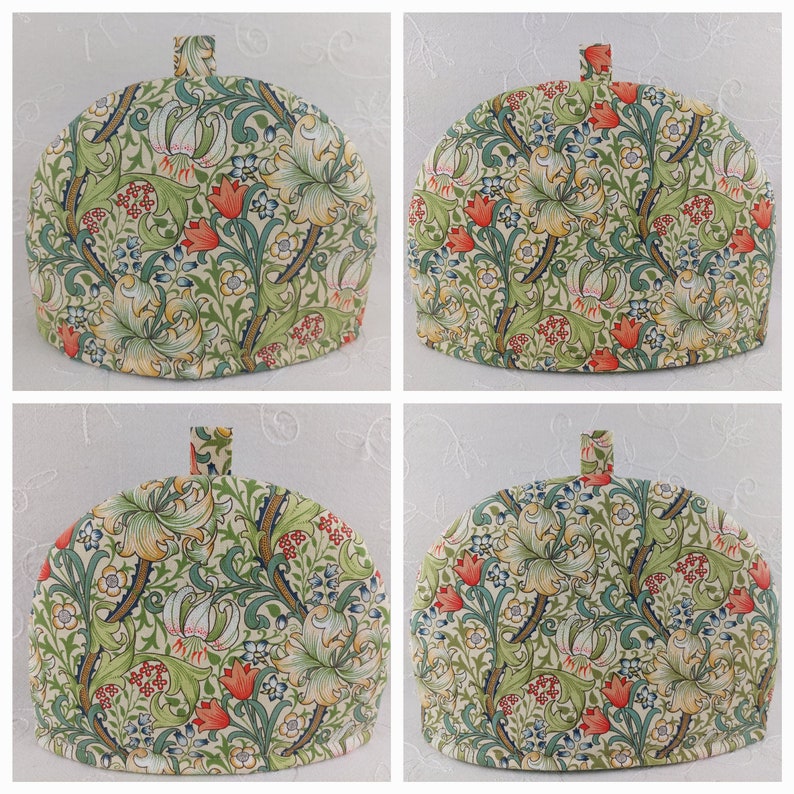 K&ouml;nnte beinhalten: Vier Teekannen-&Uuml;berz&uuml;ge mit einem floralen Muster. Das Muster zeigt Lilien, Bl&auml;tter und kleine rote Bl&uuml;ten auf cremefarbenem Hintergrund.