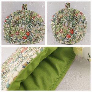 K&ouml;nnte beinhalten: Eine gr&uuml;ne und wei&szlig;e Teekanne mit einem Blumenmuster. Die Teekanne ist mit gr&uuml;nem Stoff gef&uuml;ttert und hat einen Griff oben.