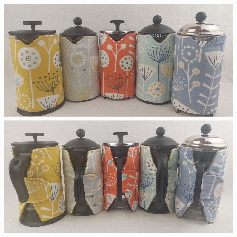 May include: Six French press coffee makers with fabric covers. The covers are in various patterns of yellow, orange, blue, and grey with a floral design.