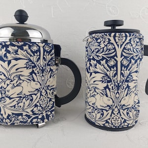 May include: Two French press coffee makers with a blue and white floral pattern featuring rabbits. The pattern is a traditional design with stylized leaves and flowers.