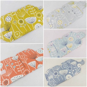 May include: Four different fabric pouches with a floral pattern. The pouches are in shades of yellow, blue, orange, and grey. The floral pattern features stylised flowers with white stems and black dots.