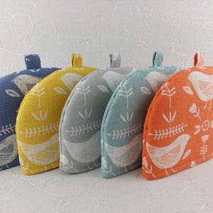 May include: Set of five tea cosy covers with a bird and floral pattern. The covers are in blue, yellow, light blue, teal, and orange.
