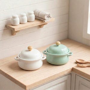 Puede incluir: Un juego de tres tazas de cerámica con un acabado mate moteado. Las tazas son de color crema, gris claro y gris oscuro. Cada taza tiene un diseño simple y minimalista y un asa redondeada.