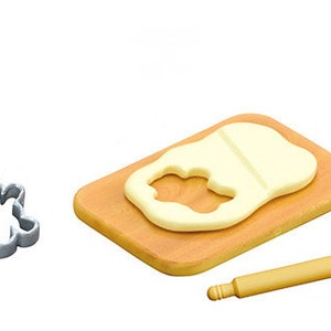 May include: A wooden rolling pin, a cookie cutter shaped like a person, and a wooden chopping board with a piece of play dough on it. The play dough has a cookie cutter shape cut out of it.