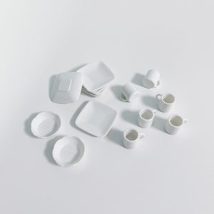 May include: A set of white ceramic dishes and cups. The set includes four small bowls, four small cups, and a stack of four plates.