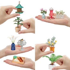 Op de afbeelding: Een set miniatuur tuindecoraties, waaronder een vogelvoederhuisje, een fontein, een potplant, een bloemstuk, een succulentenpot en een hangende lantaarn. De items zijn allemaal gemaakt van verschillende materialen, zoals metaal, plastic en hout.