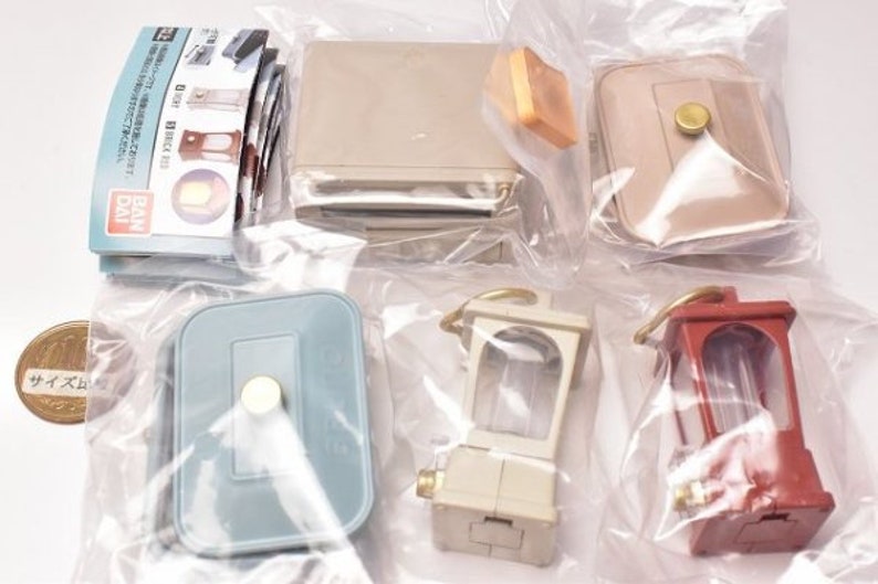 May include: A set of miniature furniture pieces, including a light blue dresser, a beige table, a beige lamp, a white lamp, and a red lamp. The furniture is packaged in clear plastic bags.