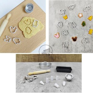 May include: Miniature baking set with a rolling pin, cookie cutters, and a small metal bowl. The set includes various cookie cutters in shapes like a bear, butterfly, and Christmas tree. The dough is ready to be cut into shapes. The set is perfect for dollhouses or craft projects.