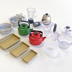 May include: A collection of miniature kitchen appliances and cookware, including a red and green tea kettle, a blender, a food processor, a measuring cup, a baking pan, and a variety of bowls.