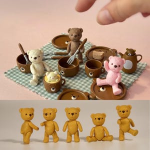 Op de afbeelding: Miniatuur teddybeer beeldjes en accessoires. De scène omvat bruine kopjes, borden en een theepot, samen met een witte, bruine en roze teddybeer. De onderste rij toont vijf gele teddybeer beeldjes in verschillende poses.