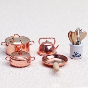 May include: A set of miniature copper kitchenware, including a teapot, two pots with lids, a frying pan, and a wooden utensil holder with a blue and white windmill design.