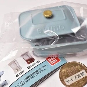 May include: A miniature light blue rectangular casserole dish with a lid and a gold-colored knob, sealed in a clear plastic bag. The item is accompanied by a Bandai product information card and a Japanese 10 yen coin for scale comparison.