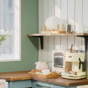 May include: A white and cream colored espresso machine with a chrome drip tray and a milk frother. The machine is sitting on a wooden countertop next to a toaster oven and a carton of milk. There is a wooden shelf above the countertop with white plates and a white mug.