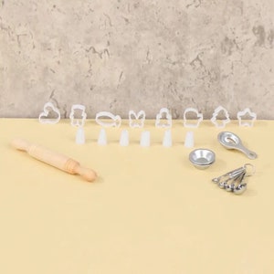 May include: A baking set with various cookie cutters in shapes like a cloud, snowman, and star. Includes a small wooden rolling pin, piping tips, measuring spoons, and a small metal bowl. Perfect for making cookies.