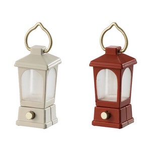 May include: Two miniature lanterns, one white and one red, with a gold handle and a clear glass window. The lanterns are on a white background.