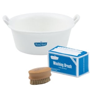 Puede incluir: Una tina de plástico blanca con dos asas, una caja de cepillo de lavado con texto azul y blanco, y un cepillo de madera marrón con cerdas.