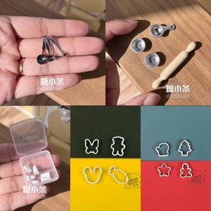 May include: Miniature kitchen tools set. Includes measuring spoons, measuring cups, a rolling pin, and cookie cutters in various shapes. The set is displayed on a wooden surface and a color-blocked background.