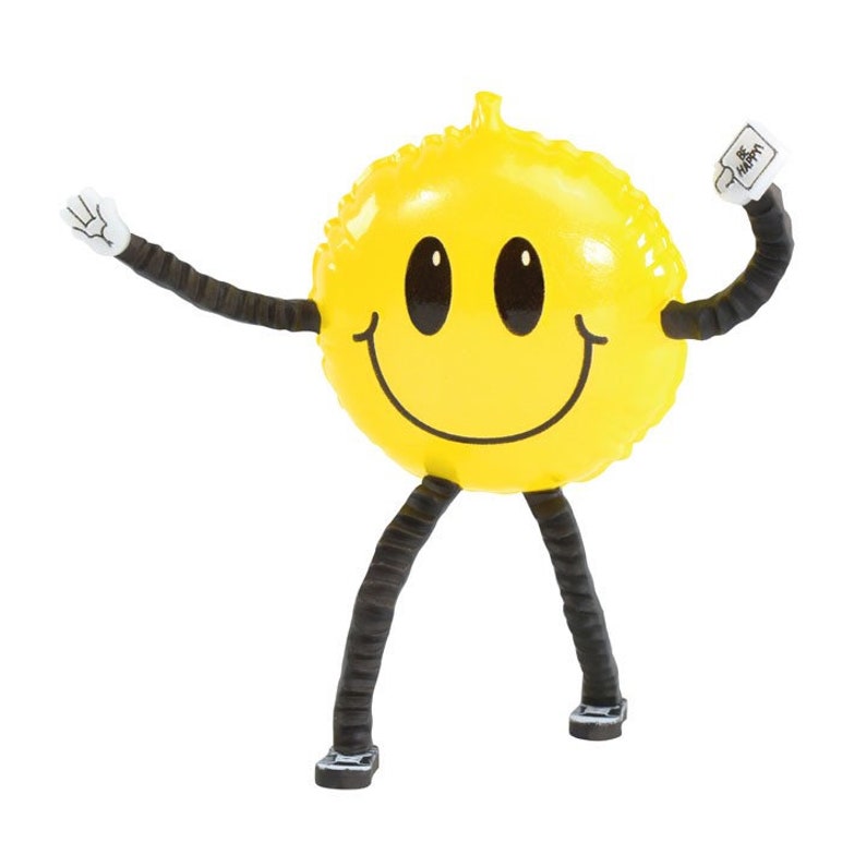 Pode incluir: Um rosto sorridente infl&aacute;vel amarelo com bra&ccedil;os e pernas pretos. O rosto sorridente est&aacute; segurando um cartaz branco que diz "Seja feliz".