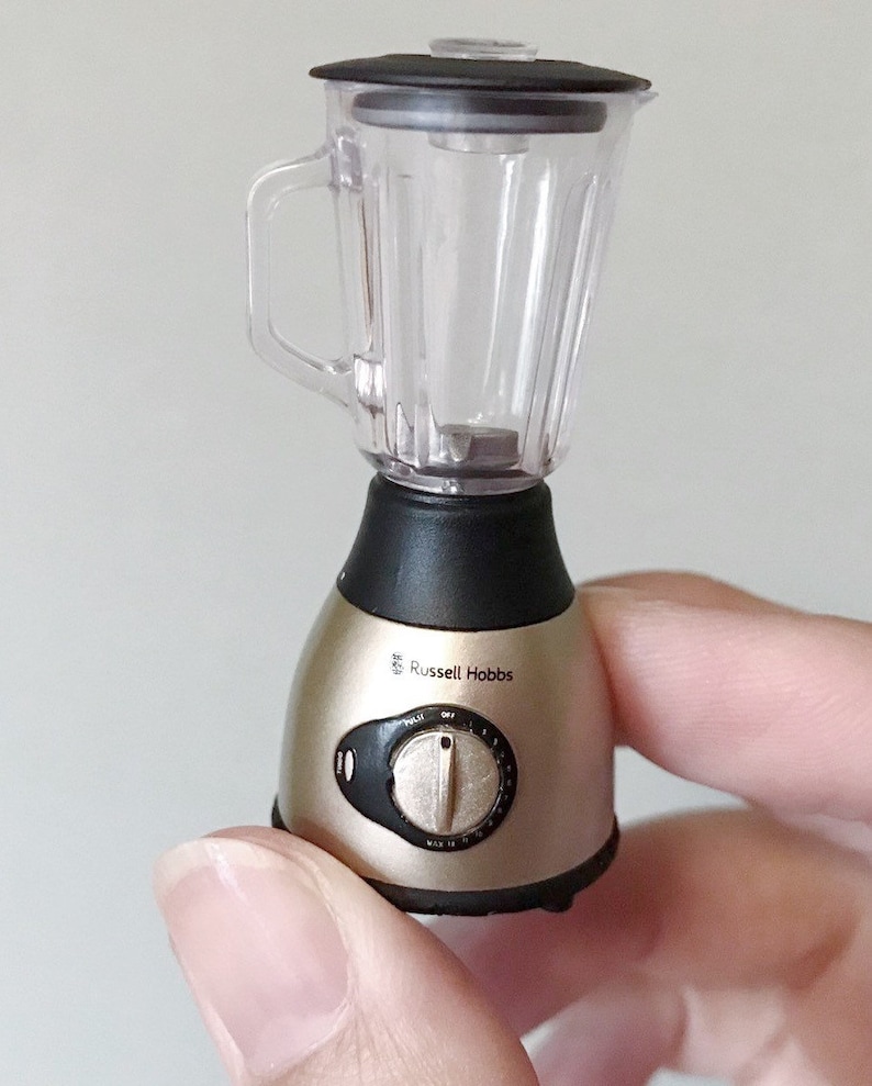 May include: A small, silver and black blender with a clear plastic container. The blender has a knob with settings for "Pulse", "Off", and "Max" and the brand name "Russell Hobbs" is printed on the side.