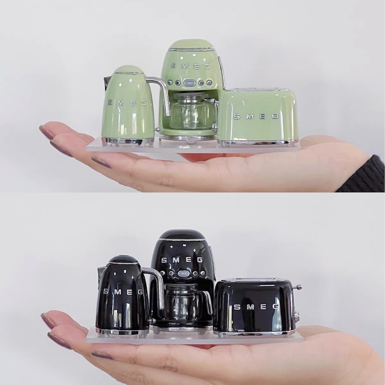 Peut inclure: Ensemble de petits appareils de cuisine vert pastel et noir. L'ensemble comprend une bouilloire, une cafeti&egrave;re et un grille-pain. Les appareils sont pr&eacute;sent&eacute;s sur un plateau transparent. La marque "SMEG" est visible sur chaque appareil.