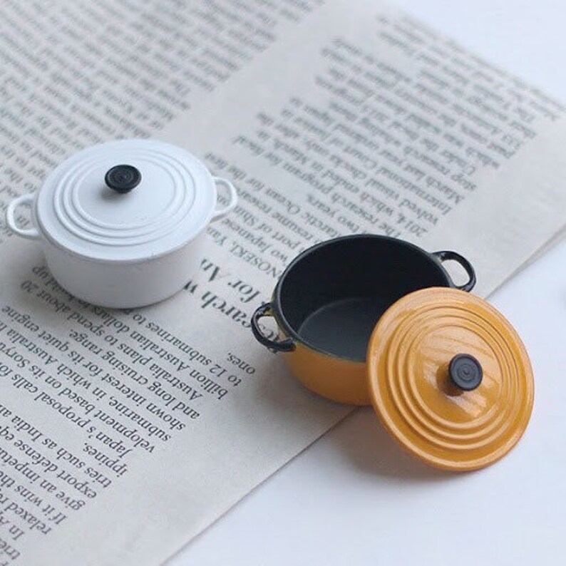 May include: A set of three ceramic mugs with a speckled, matte finish. The mugs are in shades of cream, light gray, and dark gray. Each mug has a simple, minimalist design and a rounded handle. The mugs are likely for coffee or tea.