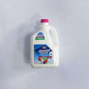 May include: A white plastic jug of Almond Breeze unsweetened almond milk. The jug has a pink cap and a handle. The label features a blue diamond with the brand name and images of almonds.