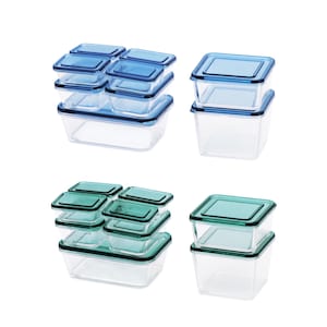 Op de afbeelding: Set van vier doorzichtige plastic voedselcontainers met blauwe en groene deksels. De containers zijn op elkaar gestapeld.