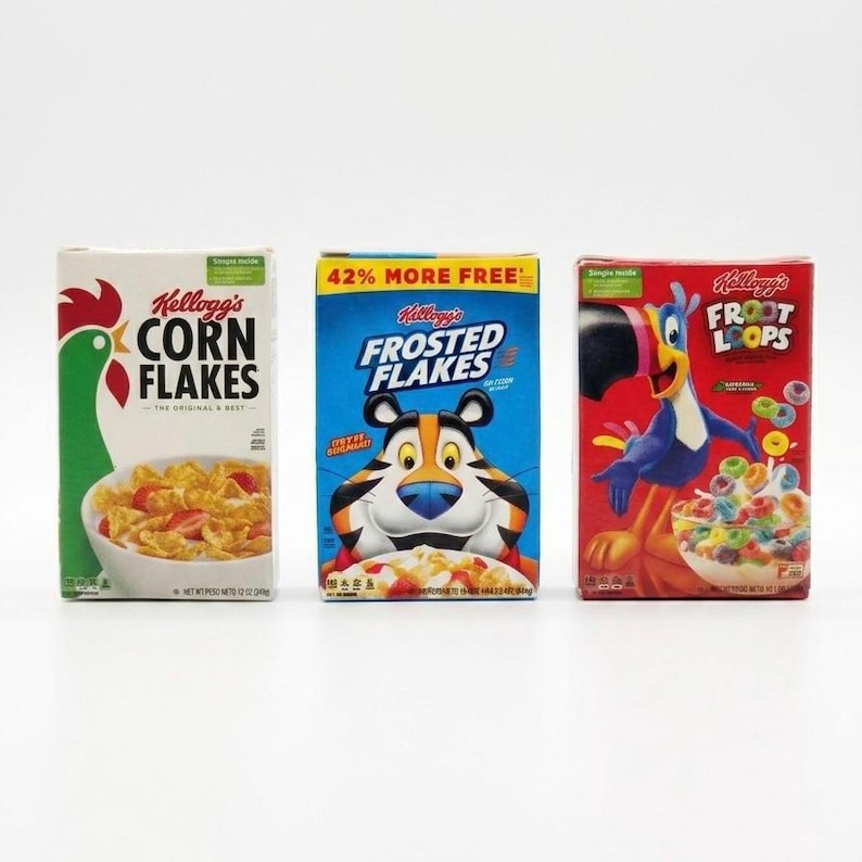 May include: Three boxes of Kellogg's cereal are displayed. The boxes are for Corn Flakes, Frosted Flakes, and Froot Loops. The Corn Flakes box is white with a green rooster. The Frosted Flakes box is blue with a tiger. The Froot Loops box is red with a toucan.