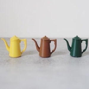 Peut inclure: Trois petites cafetières en céramique de couleur jaune, marron et verte.