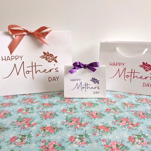A selection of white gift bags with the text "Happy Mother's Day" and a rose design. The bags are in 3 different sizes.
