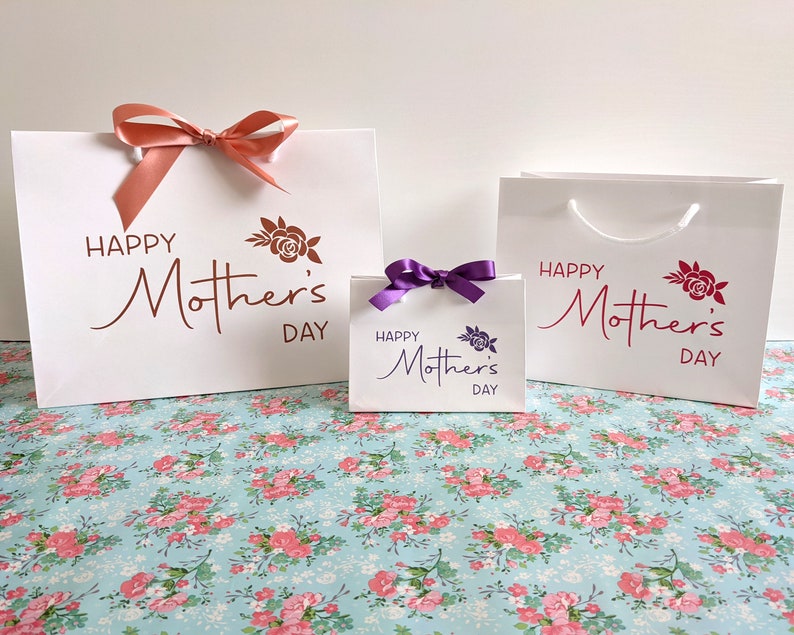A selection of white gift bags with the text "Happy Mother's Day" and a rose design. The bags are in 3 different sizes.