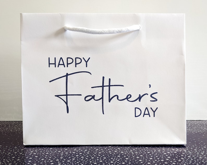 White gift bag with a blue inscription that reads "Happy Father's Day".