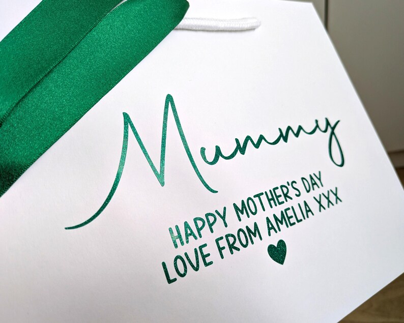 White gift bag with green Glitter text. Mummy is in a large cursive font, and below in smaller text reads "Happy Mother's Day" and a personalised message.