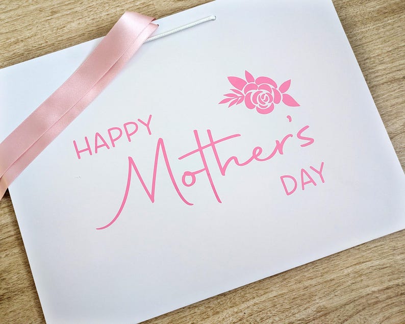 Mothers Day gift bag with pink text and ribbon.
